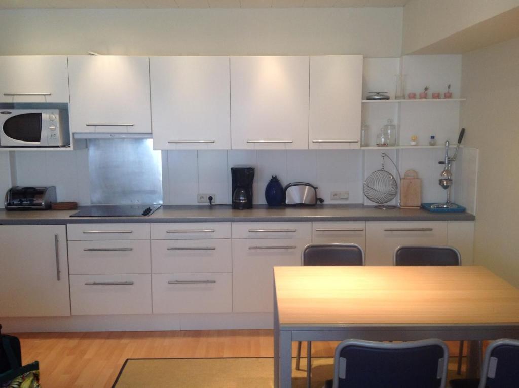 cocina con armarios blancos y mesa de madera en Rustig, kindvriendelijk appartement, en Ostende