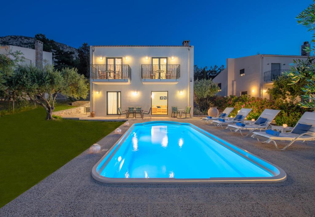 a villa with a swimming pool in front of a house at Nefeli Villas in Hersonissos