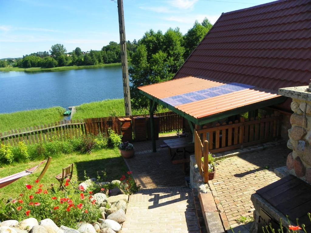 a patio with a roof with a view of a lake at Dom Letniskowy Ostaszewo in Hartowiec