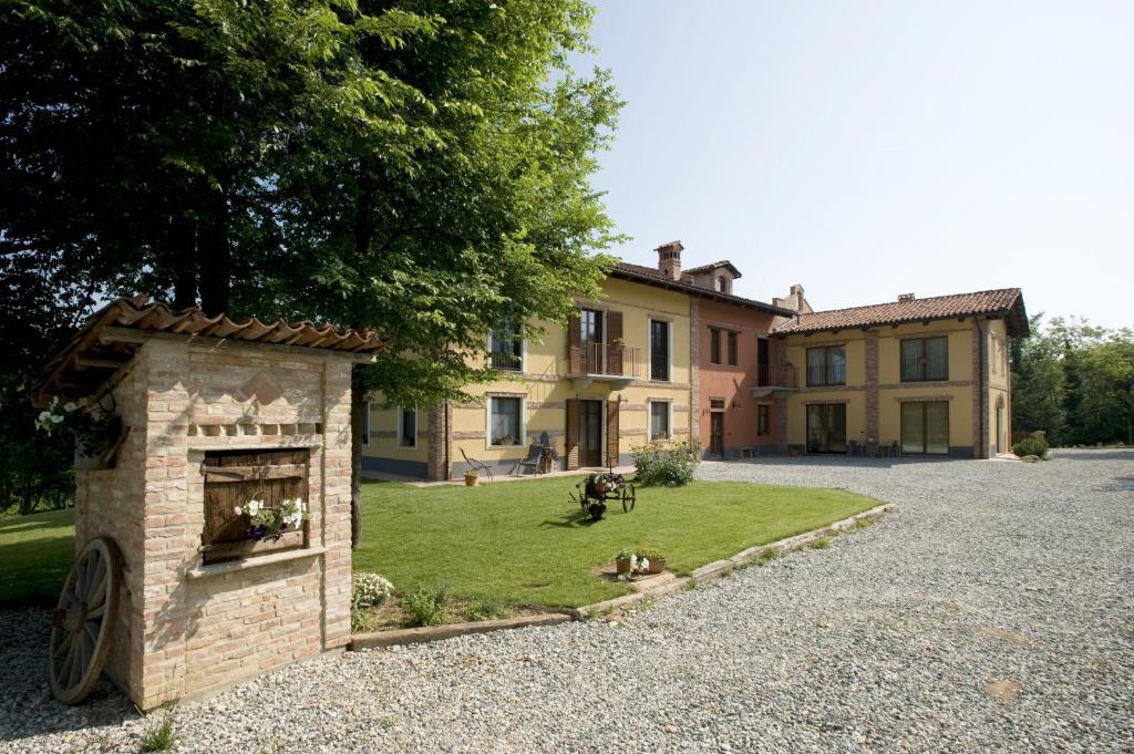 a house with a brick fireplace in front of a yard at Agriturismo Cascina Monchiero in Bra