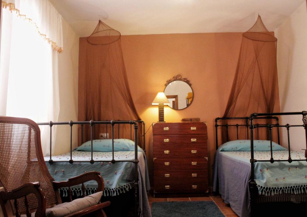 a bedroom with two beds and a dresser and a mirror at Casa Rural Los Membrillos in Teba