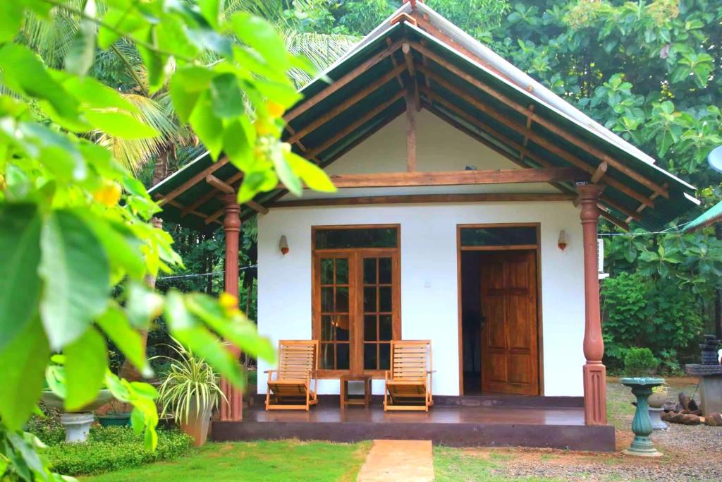 ein kleines Haus mit zwei Stühlen davor in der Unterkunft Green View Safari Resort in Udawalawe