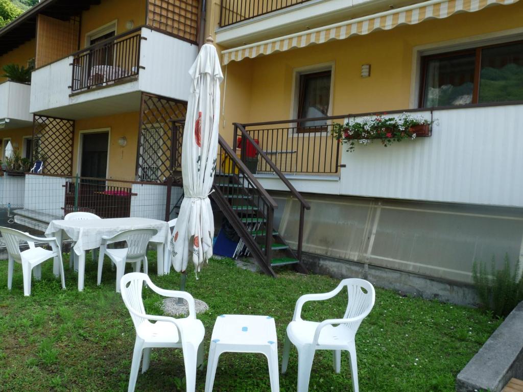 um grupo de mesas e cadeiras brancas e um guarda-chuva em Appartamento Mora em Tenno