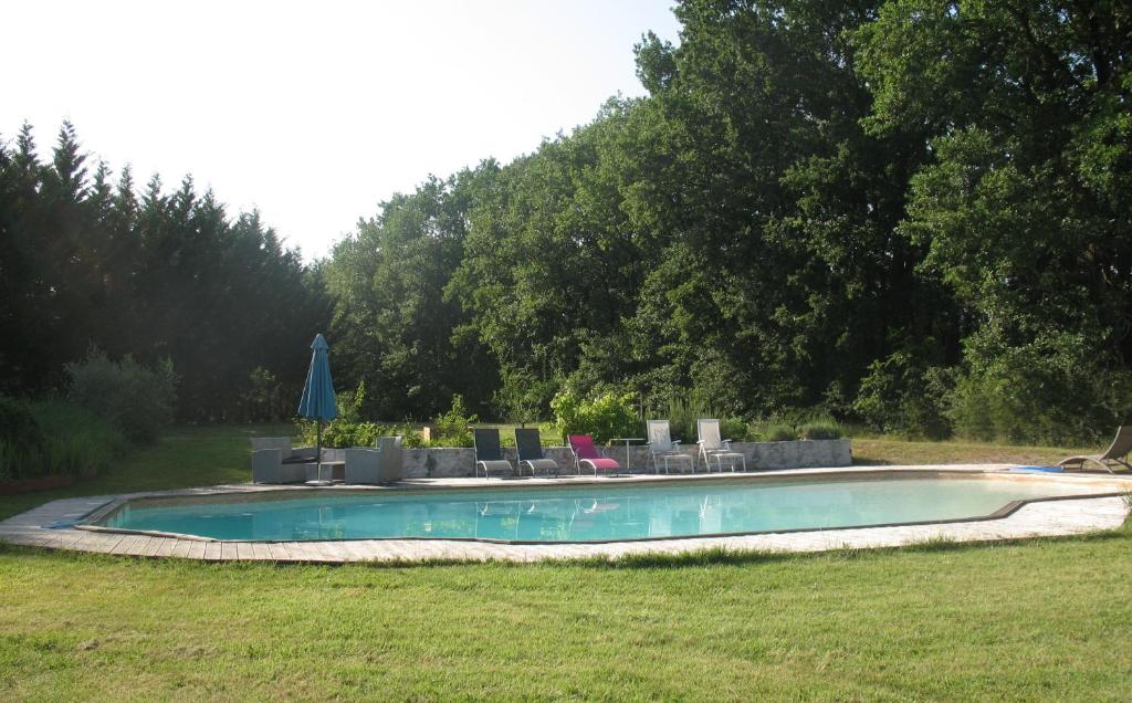 a swimming pool with chairs and umbrellas in a yard at La Pierre Blanche in La Sauvetat-sur-Lède