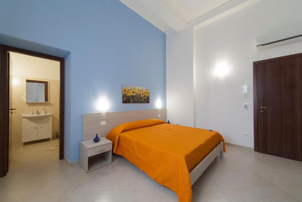 a bedroom with a bed with an orange blanket at Sole di Trapani in Trapani