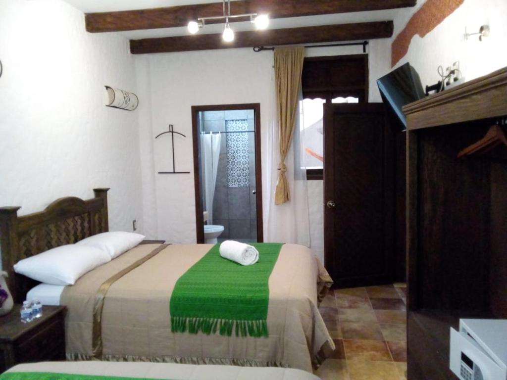 a bedroom with a bed with a green blanket at Hotel Na´Lum in San Cristóbal de Las Casas