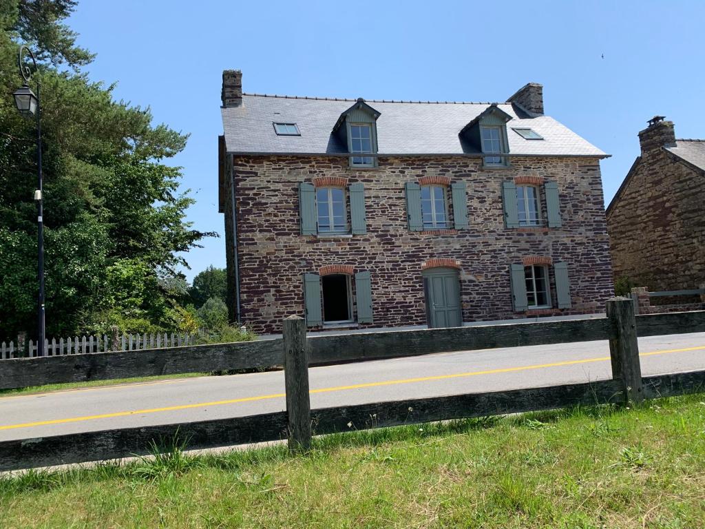 ein altes Backsteinhaus am Straßenrand in der Unterkunft La maison des Légendes in Paimpont