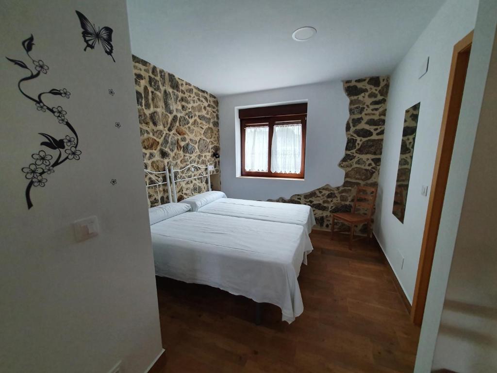 1 dormitorio con cama y pared de piedra en BIULES - LA COLINA, en Arnuero
