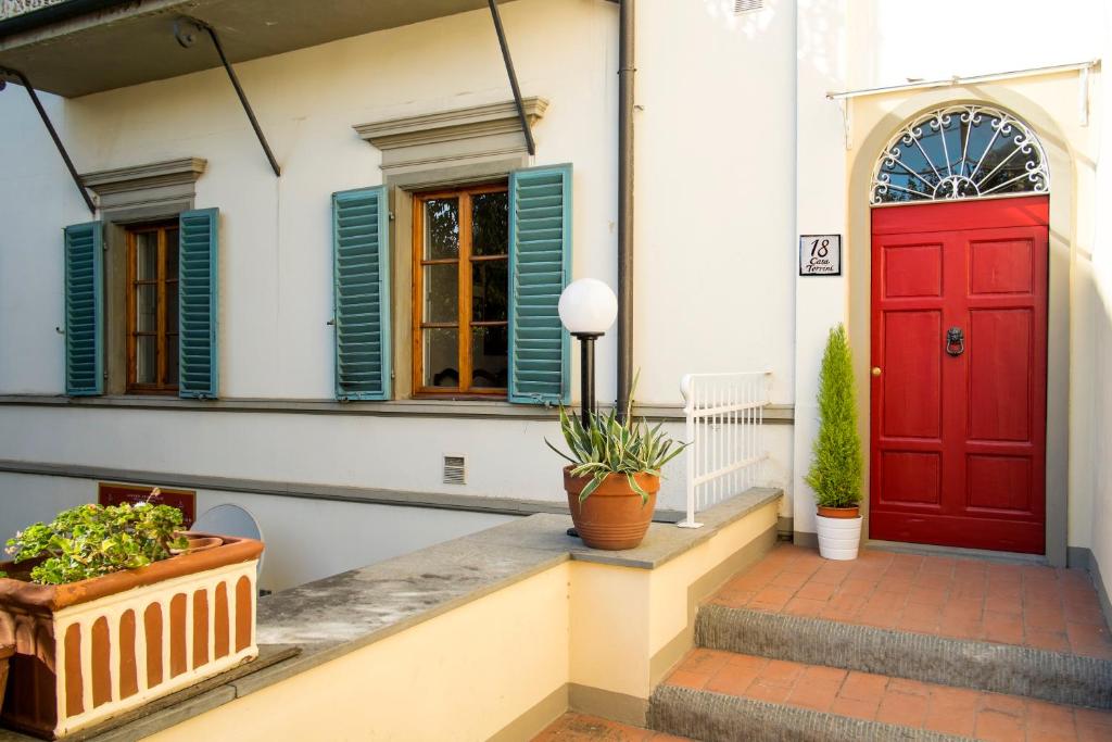uma porta vermelha numa casa branca com vasos de plantas em Casa Torrini em Fiesole