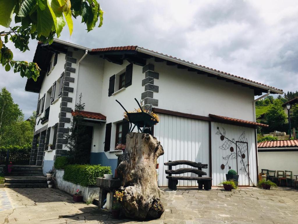 una casa con un tronco de árbol delante de ella en EKIALDE rural en Arantza