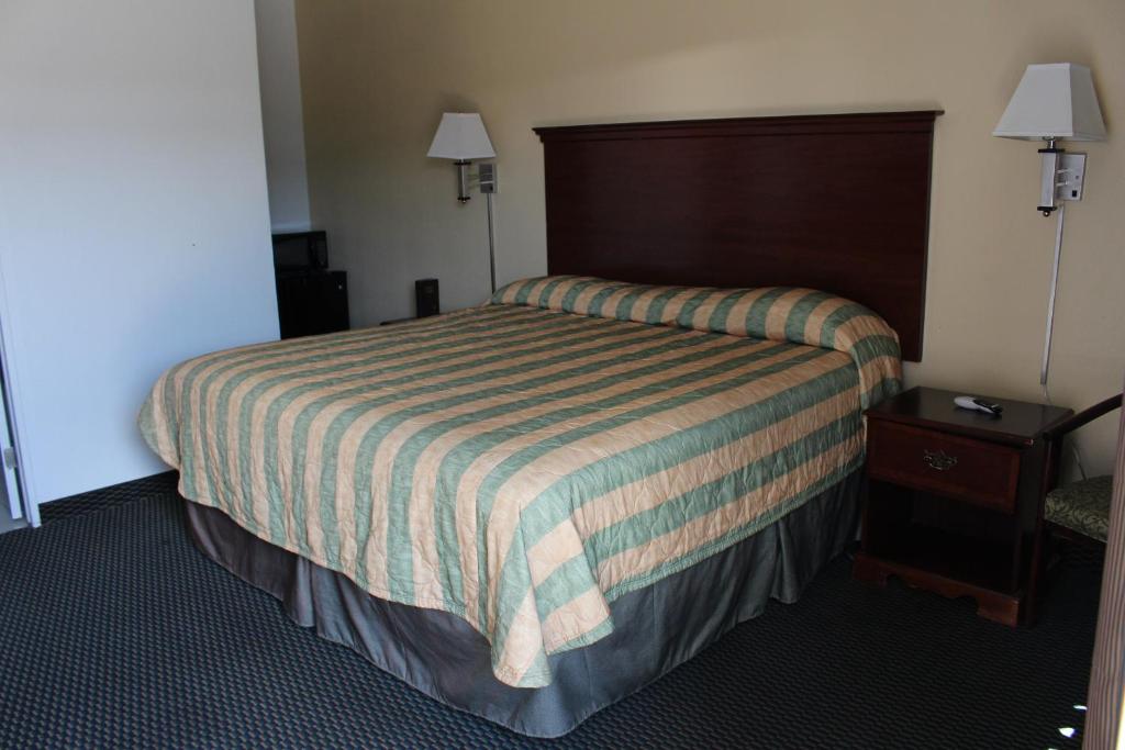 a hotel room with a bed and a night stand at Deluxe Inn Fort Stockton in Fort Stockton