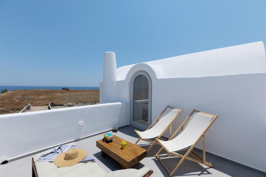 einen Balkon mit Stühlen und einem Tisch auf einem Haus in der Unterkunft Bianco Diverso Suites in Imerovigli