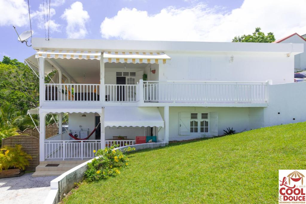 a white house with a balcony and a lawn at Kouleur Karayib in Le Gosier