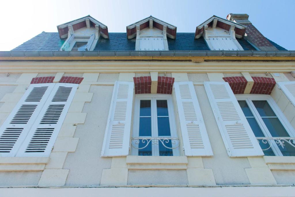 un bâtiment avec des fenêtres blanches à volets et un toit dans l'établissement Villa Clarisse, à Deauville