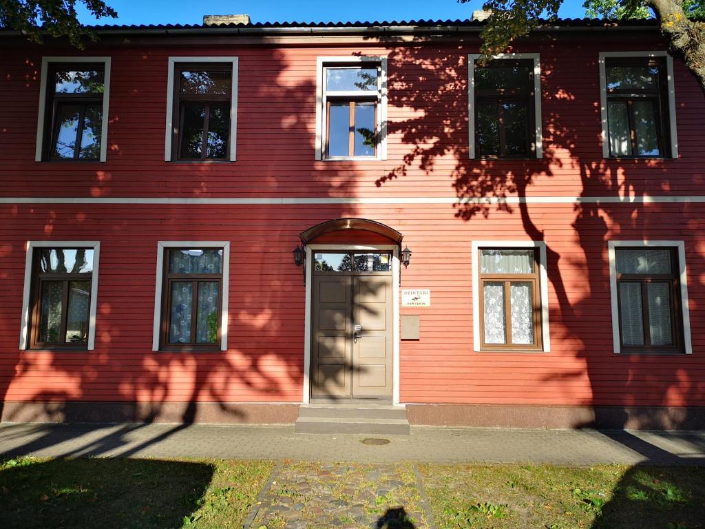 uma casa vermelha com uma porta em frente em Dzintari em Ventspils
