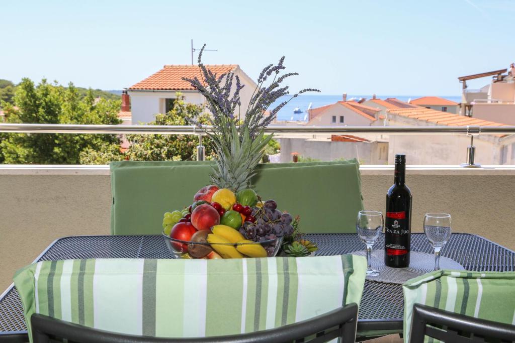 a bowl of fruit on a table with a bottle of wine at Apartments Paradise Hvar in Hvar