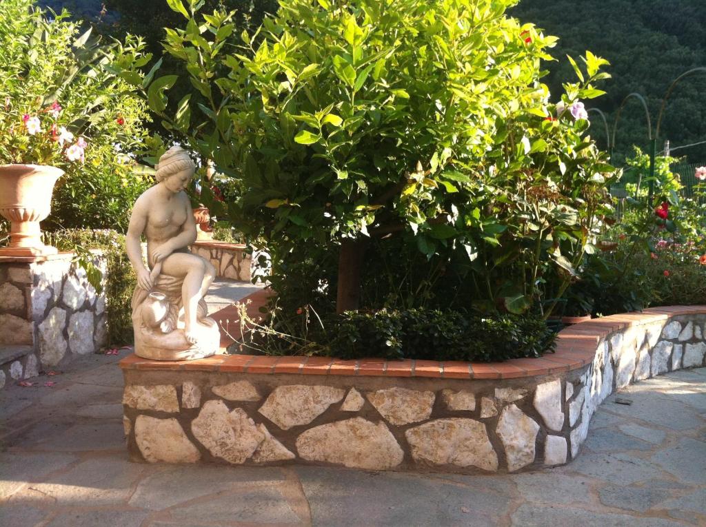 a statue of a boy sitting on a stone planter in a garden at B&B Palazzo a Mare in Capri