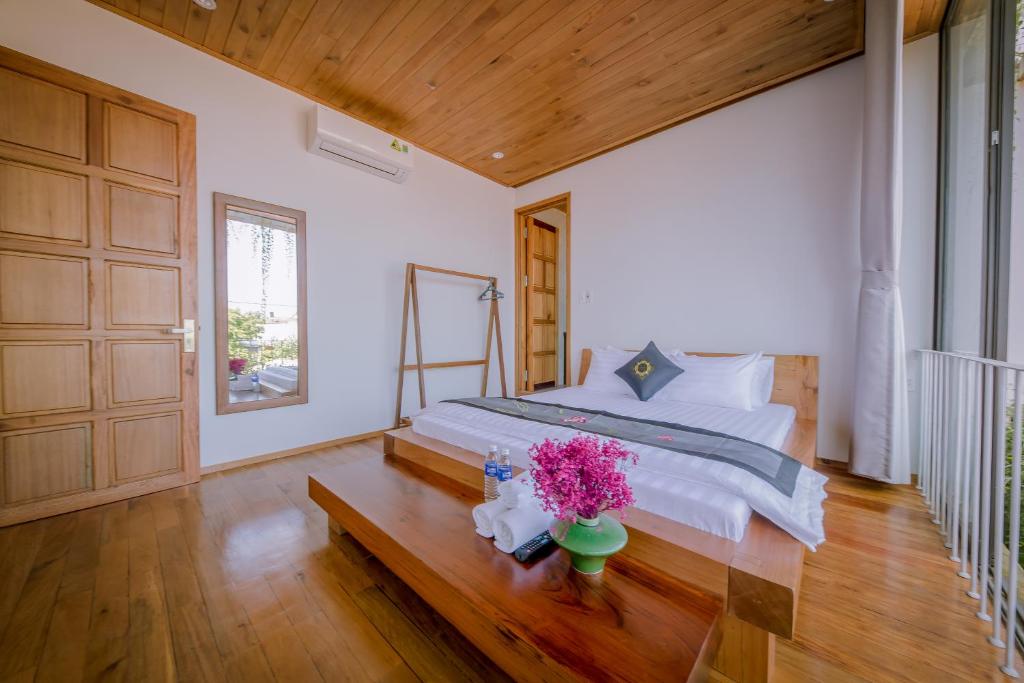 sypialnia z łóżkiem i kwiatami na drewnianej podłodze w obiekcie The Purple Hue Homestay w mieście Hue