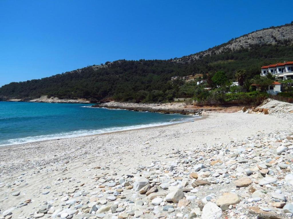 uma praia arenosa com rochas e o oceano em Villa Glaykos em Thymonia Beach