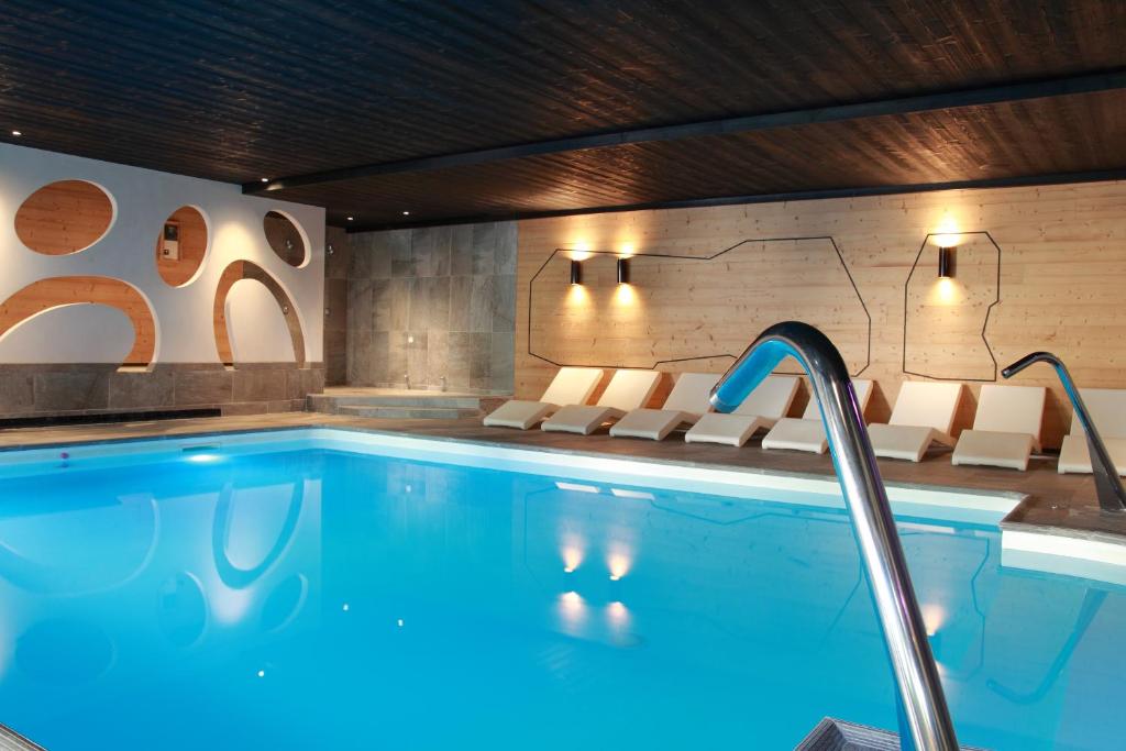 einen Pool in einem Hotelzimmer mit Stühlen und einem Pool in der Unterkunft Hotel de la Jamagne & Spa in Gérardmer