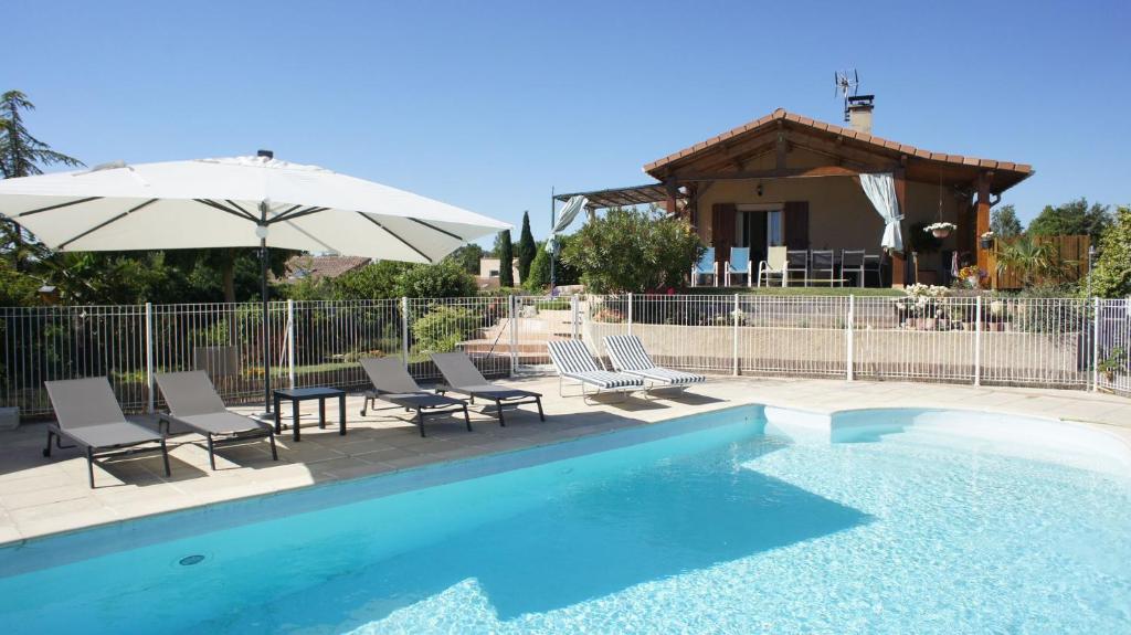 une piscine avec des chaises et un parasol ainsi qu'une maison dans l'établissement Villa privative avec grande piscine au coeur de la Drôme, à Allex