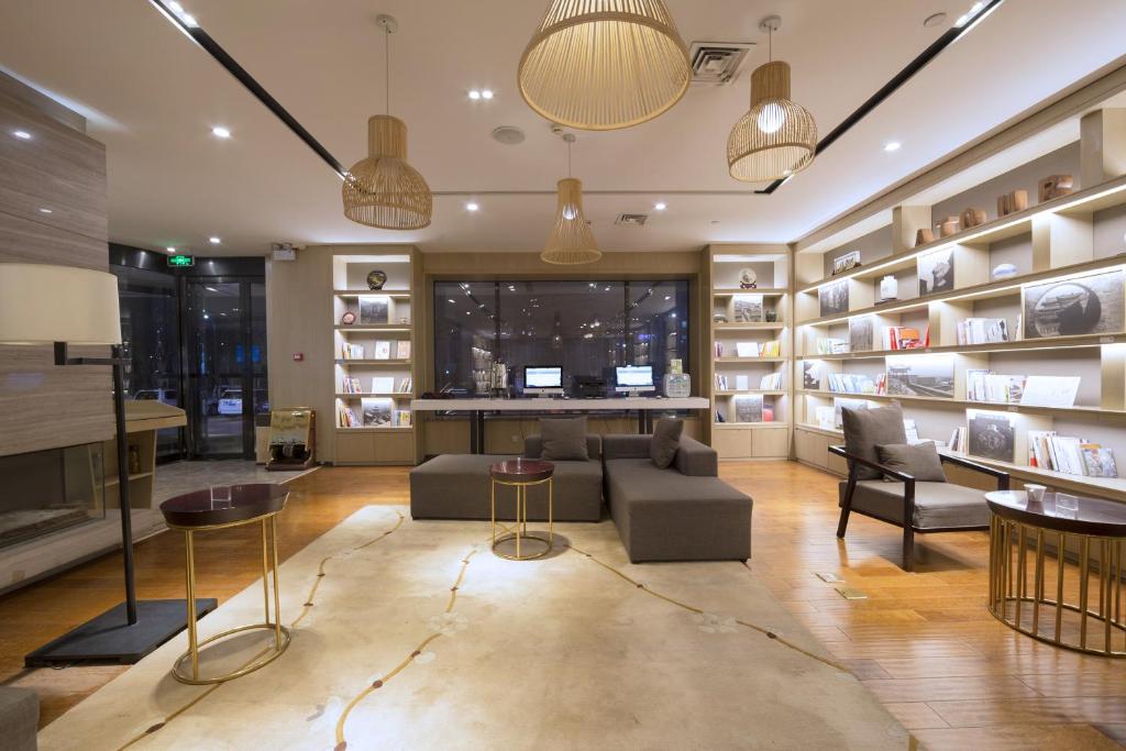 a living room with a couch and chairs and bookshelves at Atour Hotel (Taiyuan Zonggai Shifanqu) in Taiyuan