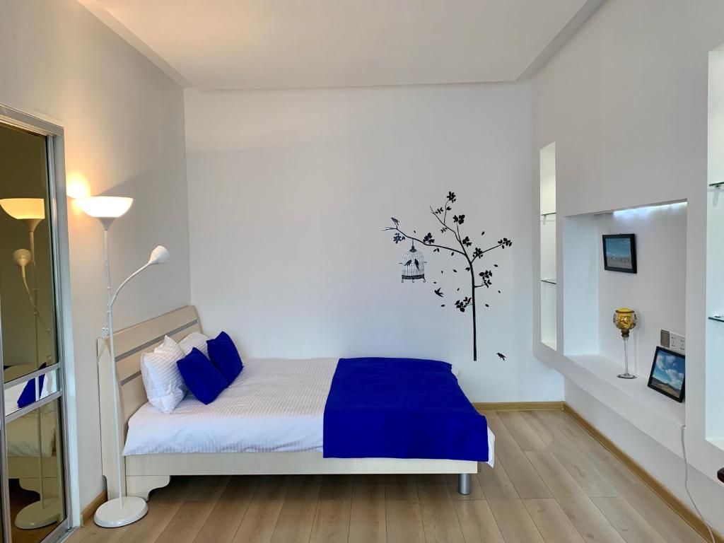 烏蘭巴托的住宿－Brilliant Location，一间卧室配有一张蓝色床单,墙上有一棵树