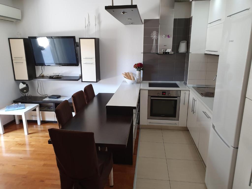 una cocina con mesa y una cocina con armarios blancos en Apartment Ivan, en Split