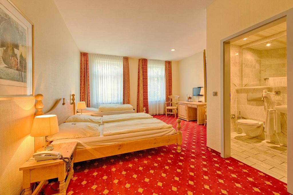 a bedroom with two beds and a bathroom at Hotel Kronprinz Garni in Minden