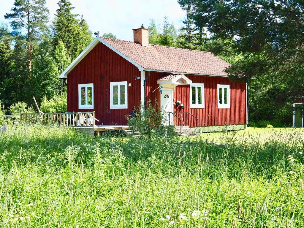 une maison rouge dans un champ d'herbe haute dans l'établissement Orsastuguthyrning-Slättberg, à Orsa