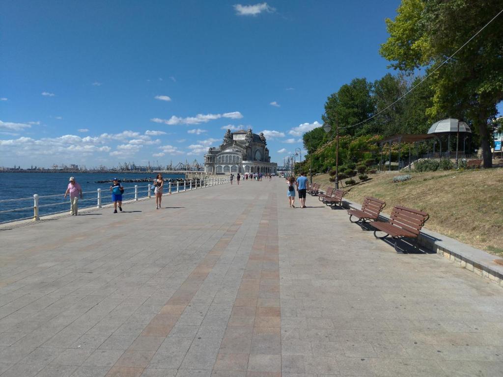 a boardwalk with benches and a building on the water at Apartament Promenada, 3 camere, langa Cazino, Faleza, Acvariu, Port Tomis, Plaja, Piata Ovidiu in Constanţa