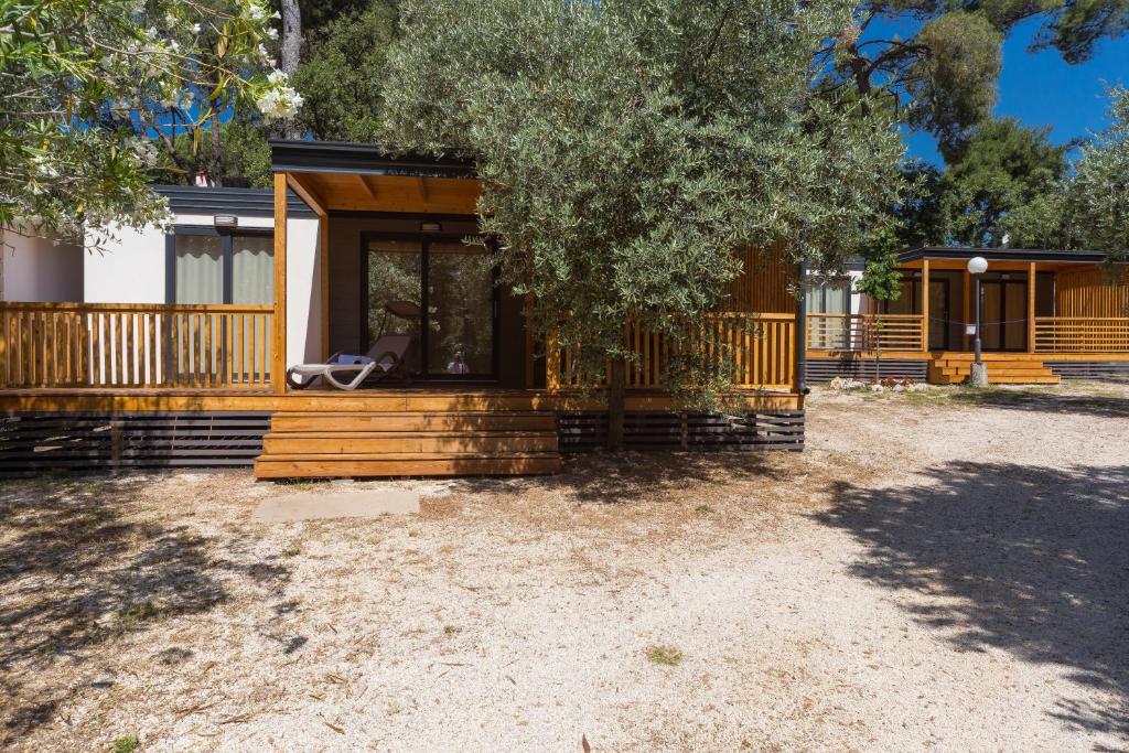 a log cabin with a porch and a tree at Diana & Josip Mobile Homes in Biograd na Moru