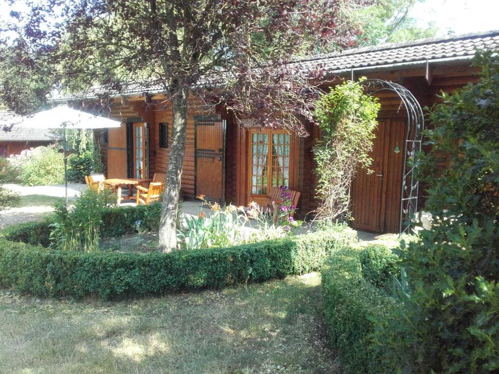 a garden with a house with a table and an umbrella at Chalet Le Paradou Adults only in Lessive