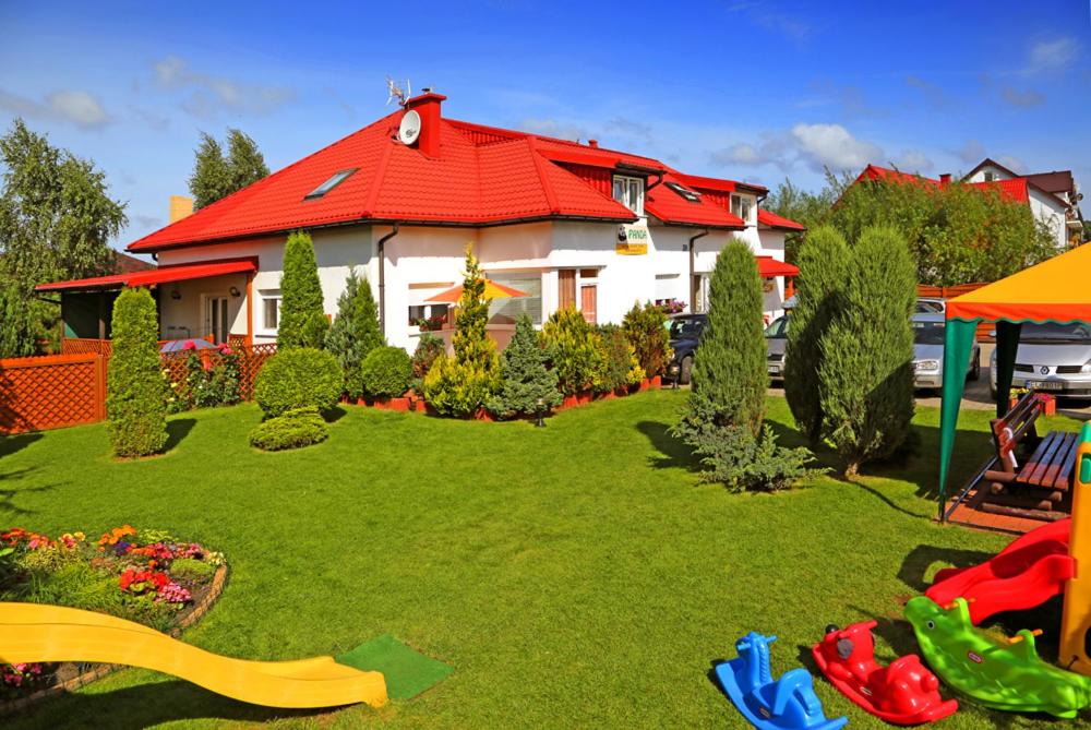 Pokoje gościnne Panda في كارفيا: منزل بسقف احمر وساحة خضراء