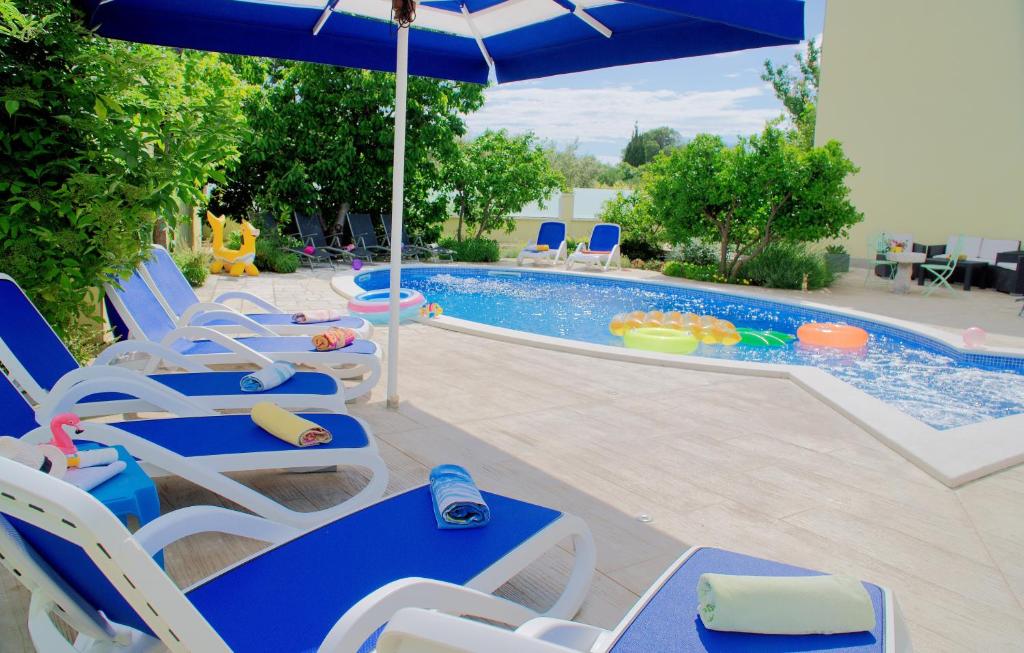 una piscina con sillas, una sombrilla y una piscina en Apartments Petra, en Trogir