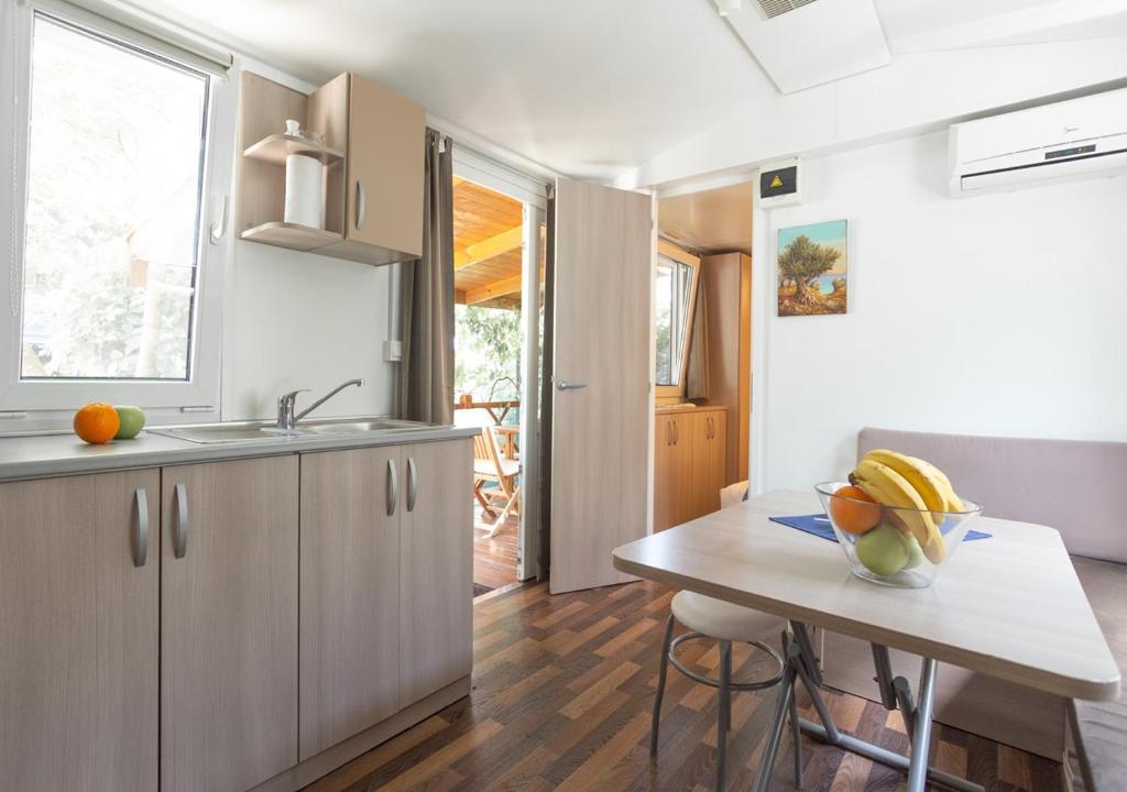 a kitchen with a table with a bowl of fruit on it at Krk Mobile Homes in Klimno
