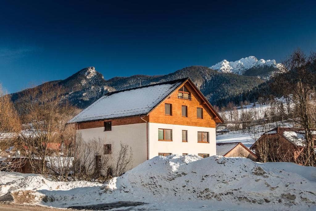 ein Haus im Schnee mit Bergen im Hintergrund in der Unterkunft Apartmány Jánošík in Terchová