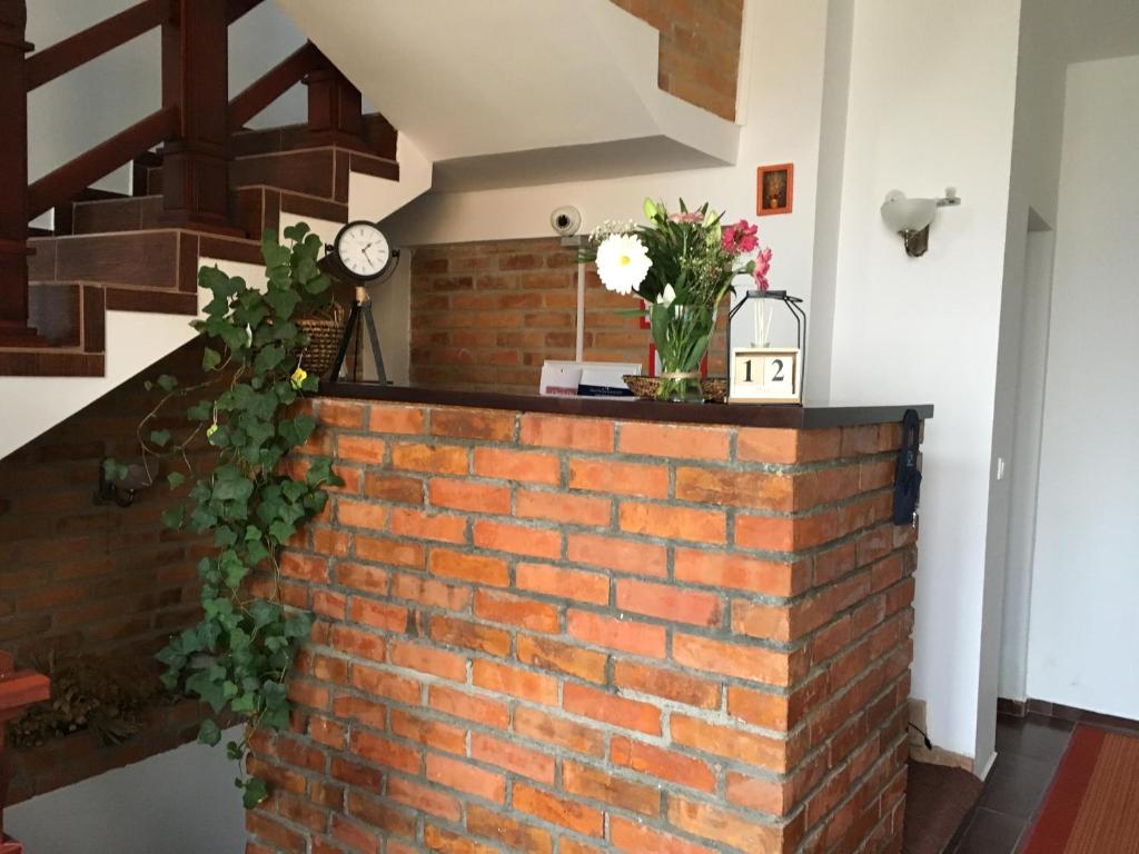 Una pared de ladrillo con un reloj y flores. en Casa Skandik Ház, en Băile Tuşnad