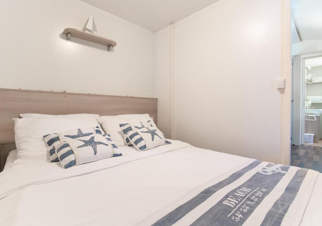 a bedroom with a white bed with blue and white pillows at Krk Mobile Homes in Klimno