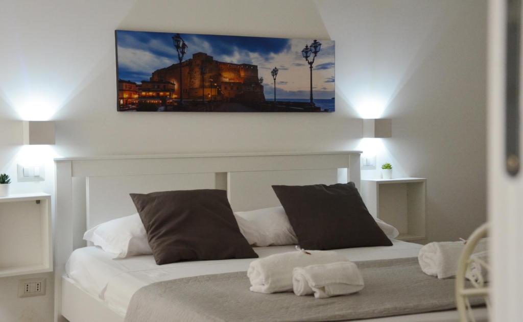 ナポリにあるMellos B&Bの白いベッド2台が備わるベッドルーム1室、壁に絵画が飾られています。