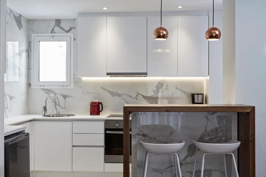 a kitchen with white cabinets and a counter with stools at Cozy and Bright 2BD Apartment in Kolonaki in Athens