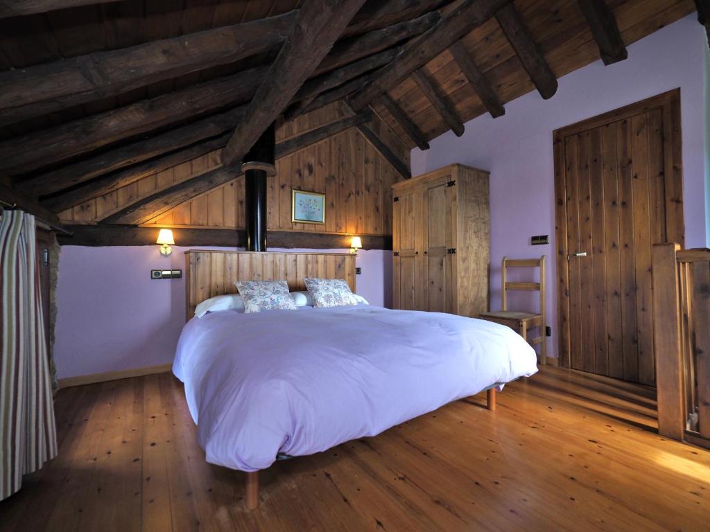 1 dormitorio con 1 cama blanca grande y suelo de madera en Los Tres Albares, en Lardiés