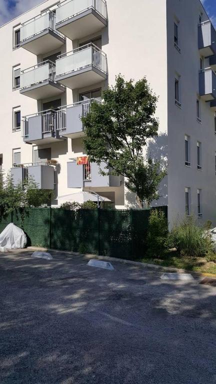 un grand bâtiment blanc avec une clôture devant lui dans l'établissement T2 Montpellier plein sud clim wifi terrasse de 16m2, à Montpellier