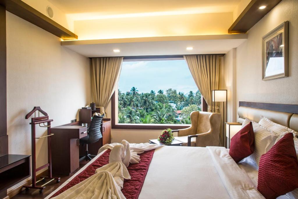 Habitación de hotel con cama grande y ventana en KPM TRIPENTA HOTEL, en Kozhikode
