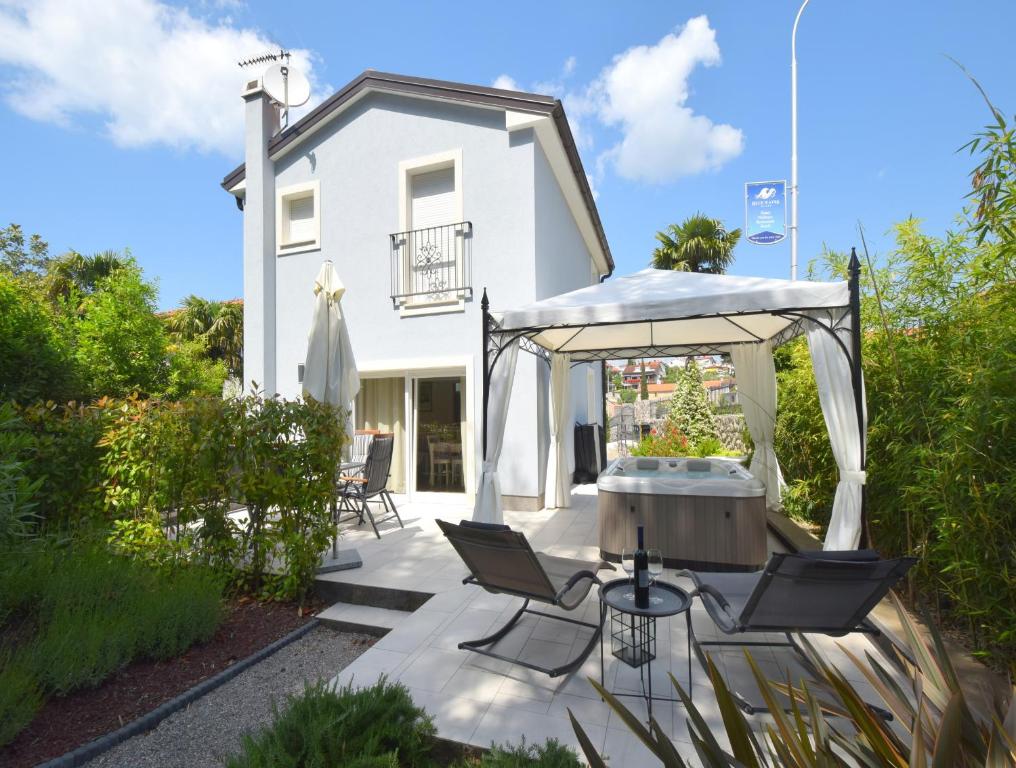 a patio with chairs and an umbrella in front of a white house at House Andrea in Malinska