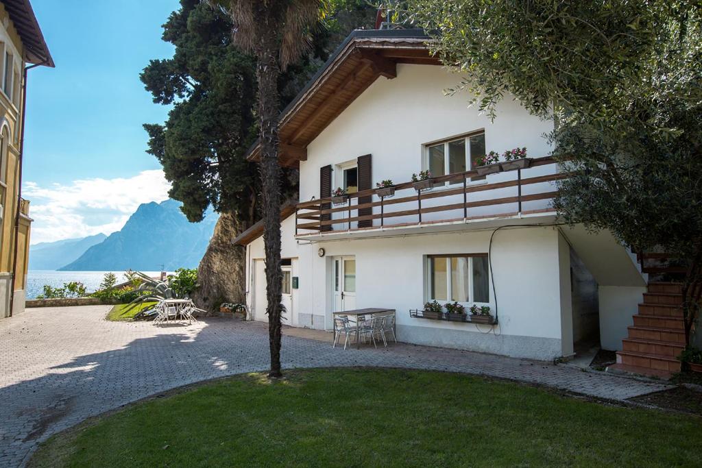 a white house with a table and chairs in a yard at Apartments Suster in Nago-Torbole