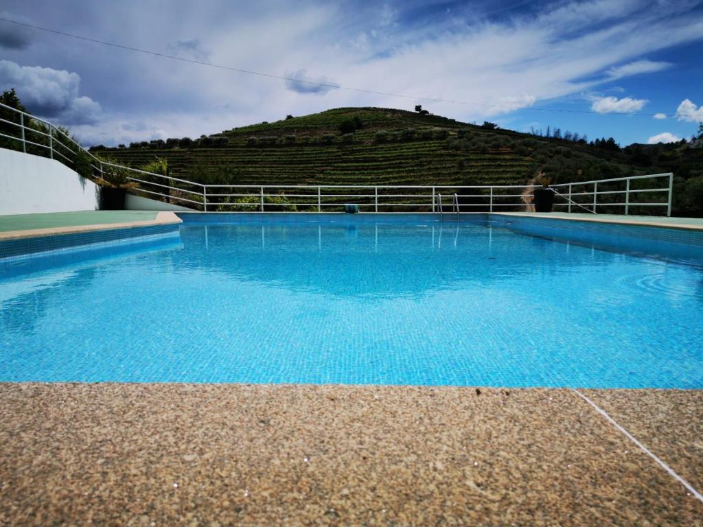 a blue swimming pool with a hill in the background at Quinta do Reconco in Santa Eugénia