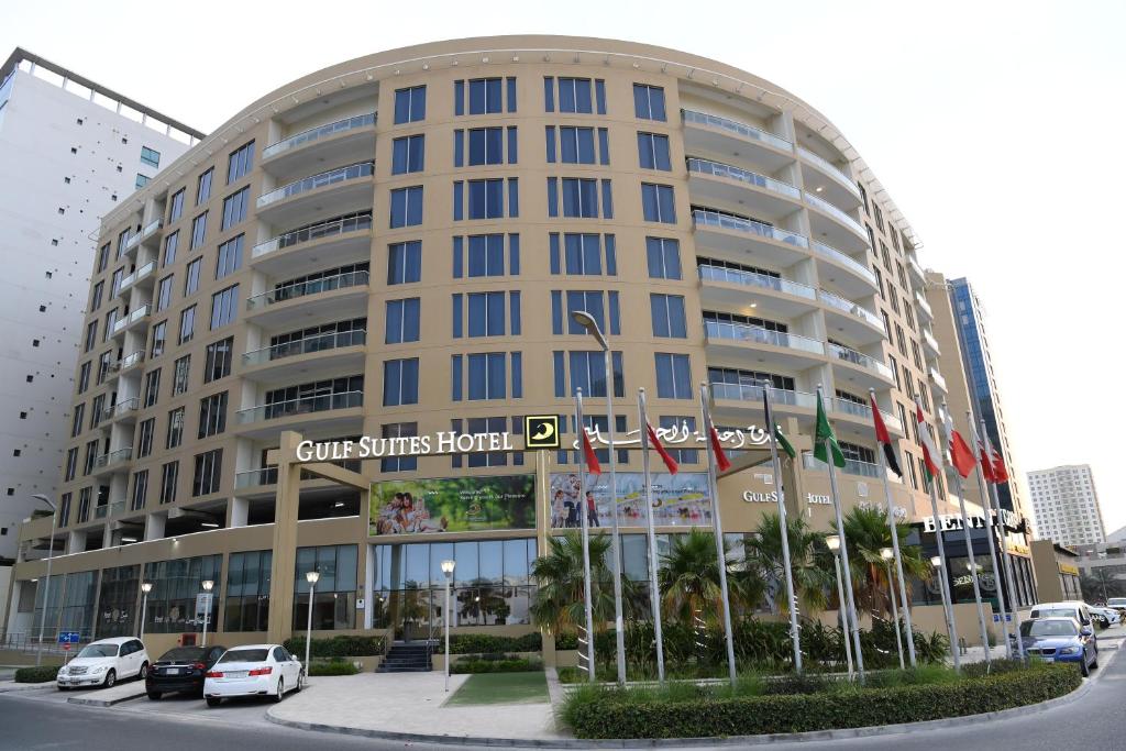 un gran edificio con coches estacionados frente a él en Gulf Suites Hotel Amwaj, en Manama