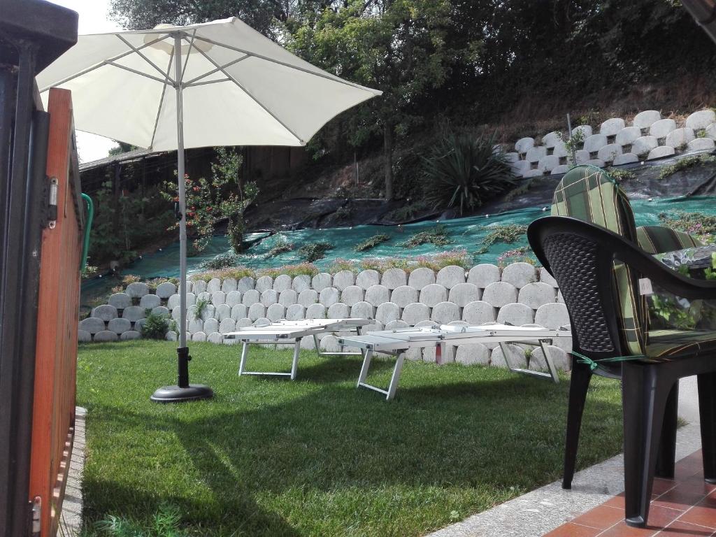 d'une terrasse avec des chaises et un parasol sur la pelouse. dans l'établissement Appartamento Trifoglio, à Salò