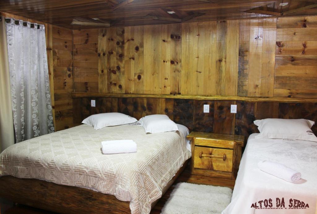 2 Betten in einem Zimmer mit Holzwänden in der Unterkunft Altos da Serra in São José dos Ausentes